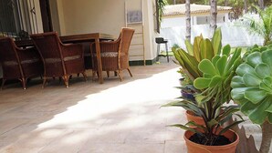 Un patio con mobiliario de mimbre y plantas en macetas.