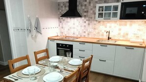 A compact kitchen with a dining area, featuring a microwave, oven, and a black range hood.