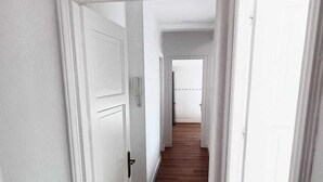 A hallway with white doors and wooden flooring.