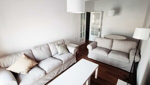 A modern living room with two sofas, a coffee table, and a lamp.