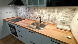 A kitchen with a wooden countertop, stainless steel sink, and light blue cabinets.