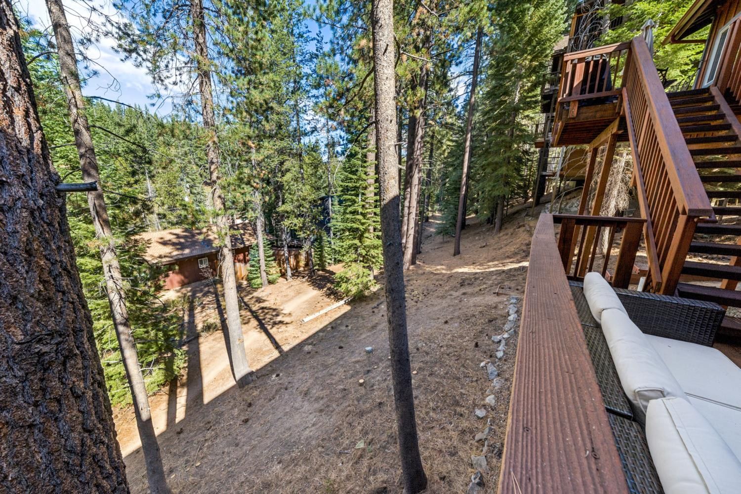 A wooden deck with a view of a forested area and a building in the background.