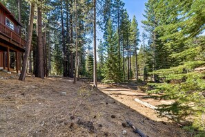 A cabin with a deck surrounded by tall pine trees. - 6BR Family Cabin | Sleeps 14 | Hot Tub + Trail (South Lake Tahoe)