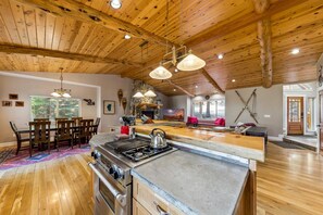 A spacious kitchen with a large island, wooden ceiling, and a dining area with a table and chairs.