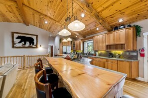 Un intérieur en bois avec une grande table à manger, des meubles de rangement en bois et une décoration murale sur le thème des ours.