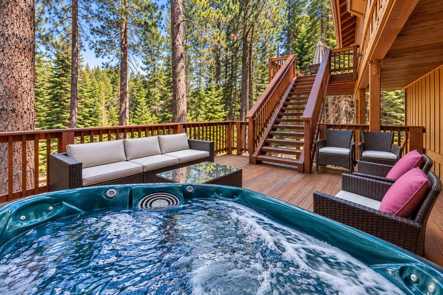 A hot tub on a wooden deck with a staircase, a sofa, and wicker chairs.