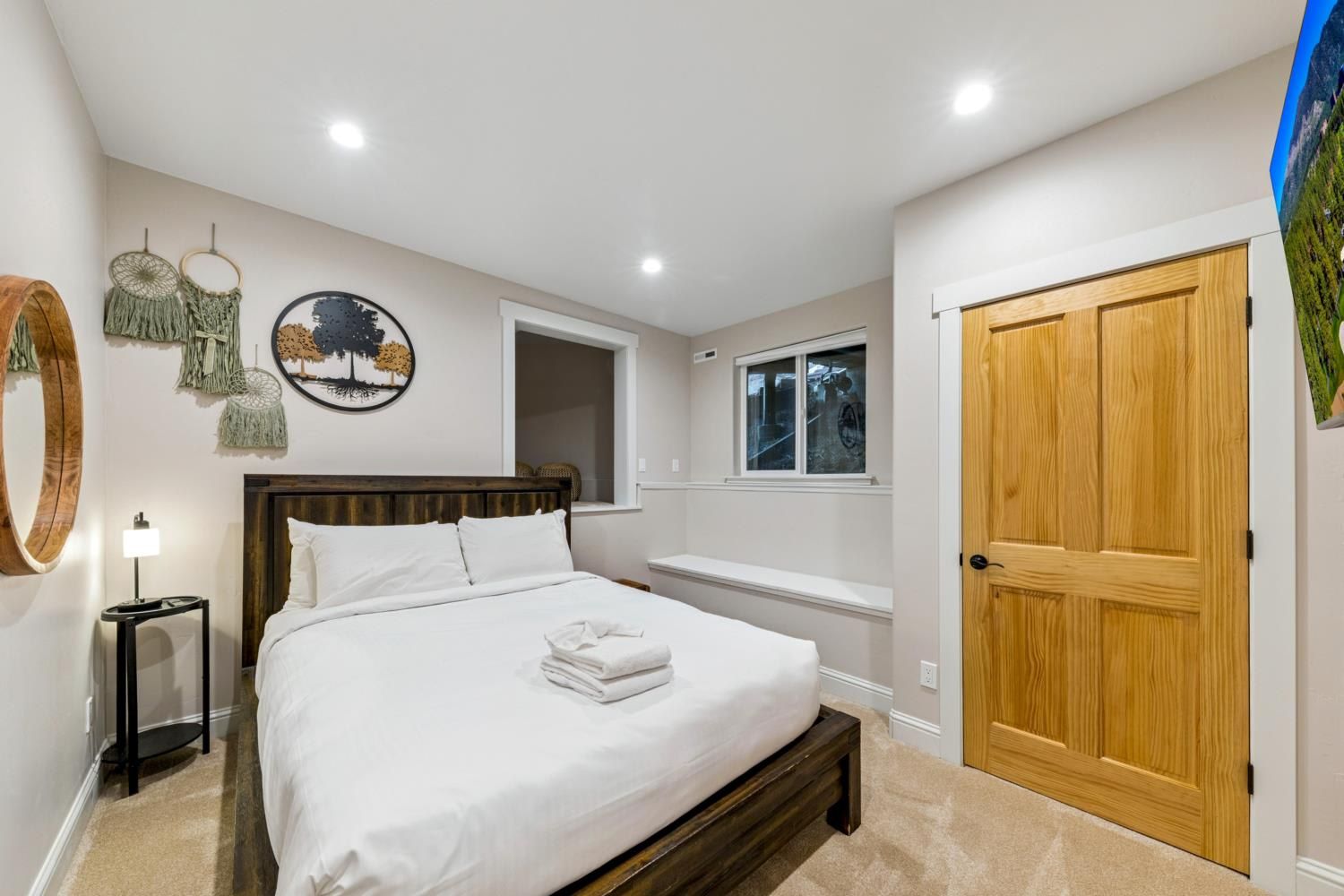 A bedroom with a bed, a wooden door, a window, and wall decorations.