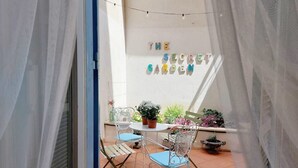 A balcony with a white table and two chairs, surrounded by potted plants and a sign reading "THE SECRET GARDEN". - LOFT WITH SECRET GARDEN AT THE COLISEUM (roma)