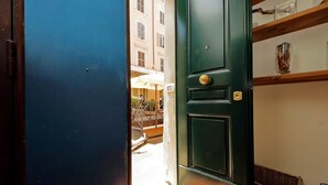 A green door with a brass handle, leading to a balcony with outdoor furniture and a building in the background. - LOFT WITH SECRET GARDEN AT THE COLISEUM (roma)