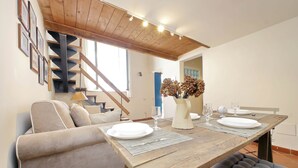 A dining area with a wooden table set for four, a sofa, and a staircase. - LOFT WITH SECRET GARDEN AT THE COLISEUM (roma)