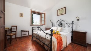 A bedroom with a bed, a chair, a nightstand, a dresser, a window, and a door.