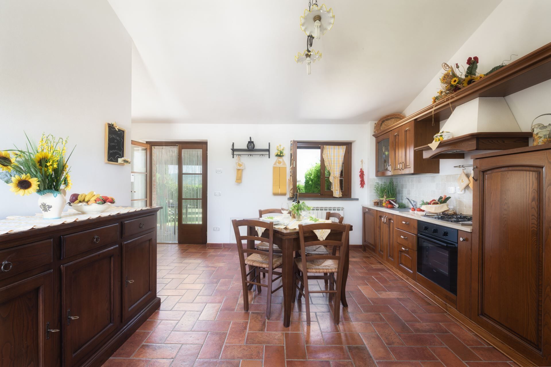 A spacious kitchen with wooden cabinets, a dining table with chairs, and a view to the outside.