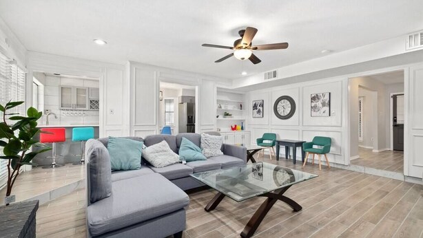 A spacious living room with a grey sectional sofa, a glass coffee table, and a ceiling fan. - 5BR 3.5BA Pool House – Comfortably Sleeps 15 (McKinney)