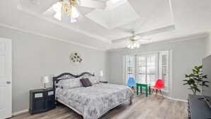 A bedroom with a bed, nightstands, a ceiling fan, a window with blinds, and a plant. - 5BR 3.5BA Pool House – Comfortably Sleeps 15 (McKinney)