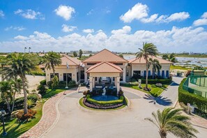 A resort with a central building, a swimming pool, and palm trees.
