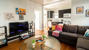 Ein modernes Wohnzimmer mit einem Flachbildfernseher, einem Glastisch und einer Couch.