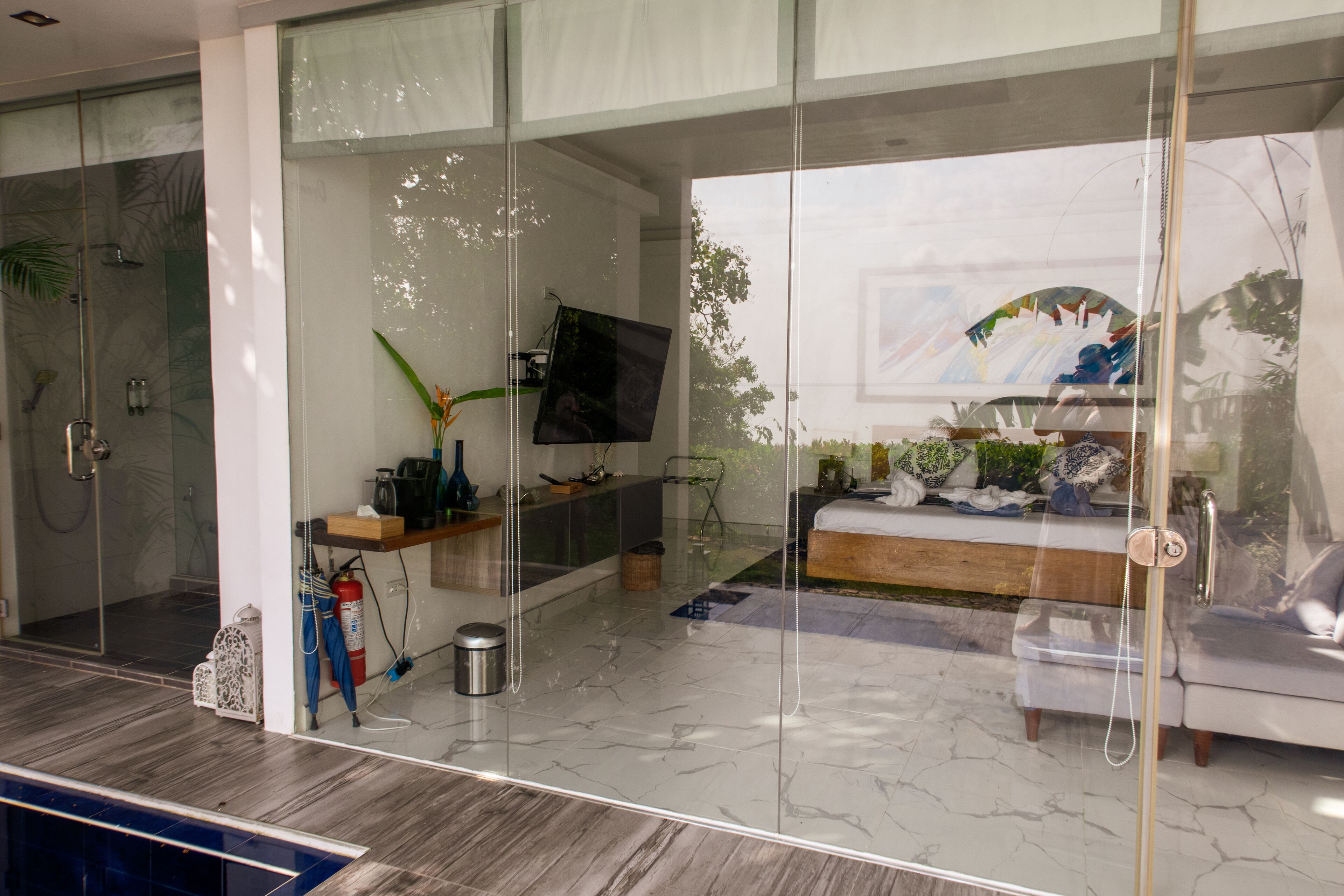 A modern living room with a glass partition, a flat-screen TV, a sofa, and a coffee table.