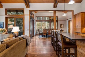 A spacious living area with a wooden dining table, a sofa, and a kitchen area with wooden cabinets.