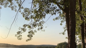 Vista di un lago con un molo, acque calme e alberi.