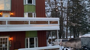 Un edificio a due piani con facciata verde e rossa, un portico coperto e dintorni innevati.