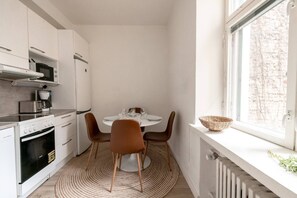 A compact kitchen with modern appliances, a dining table with chairs, and a view through a window. - 2ndhomes Cozy Studio in the Center (Helsinki)