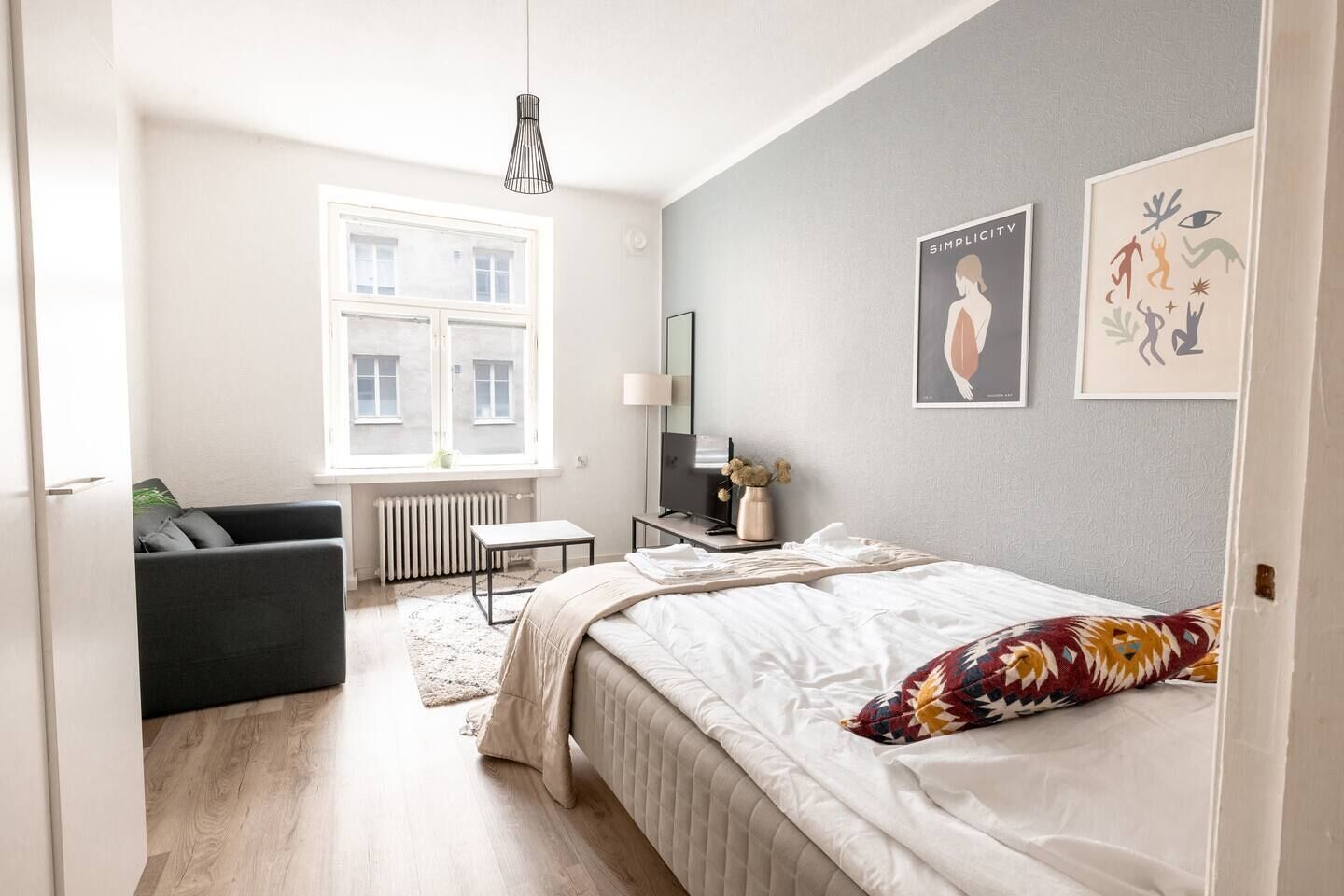 Een slaapkamer met een bed, een bureau, een stoel, een radiator en een raam.