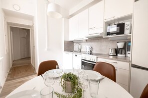 A modern kitchen with white cabinets, a microwave, a coffee maker, and a dining area with a table set for two.