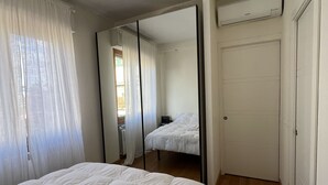 Ein Schlafzimmer mit einem Bett, einem Spiegel, einer Heizung und einer Tür.