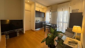 Eine moderne Wohnung mit Wohnzimmer, Essbereich, Küche und Fernseher.