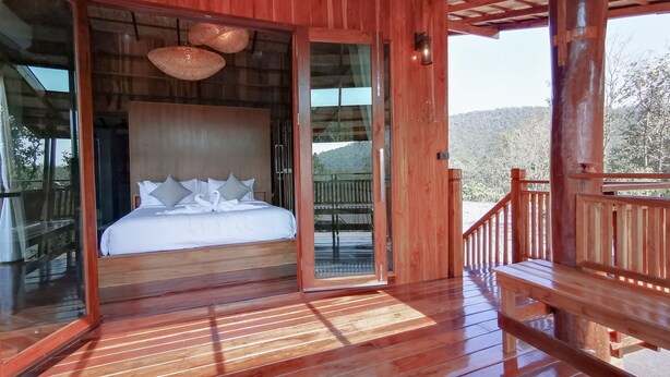 Una cabaña de madera con una cama, un balcón y vistas al exterior.