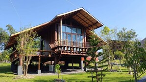 Una casa de madera de dos pisos con balcón, rodeada de un jardín cuidado.
