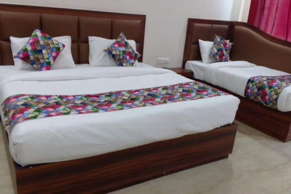 Quarto de hotel com duas camas, cada uma com cabeceira de madeira, roupa de cama branca e colchas estampadas em cores vibrantes.