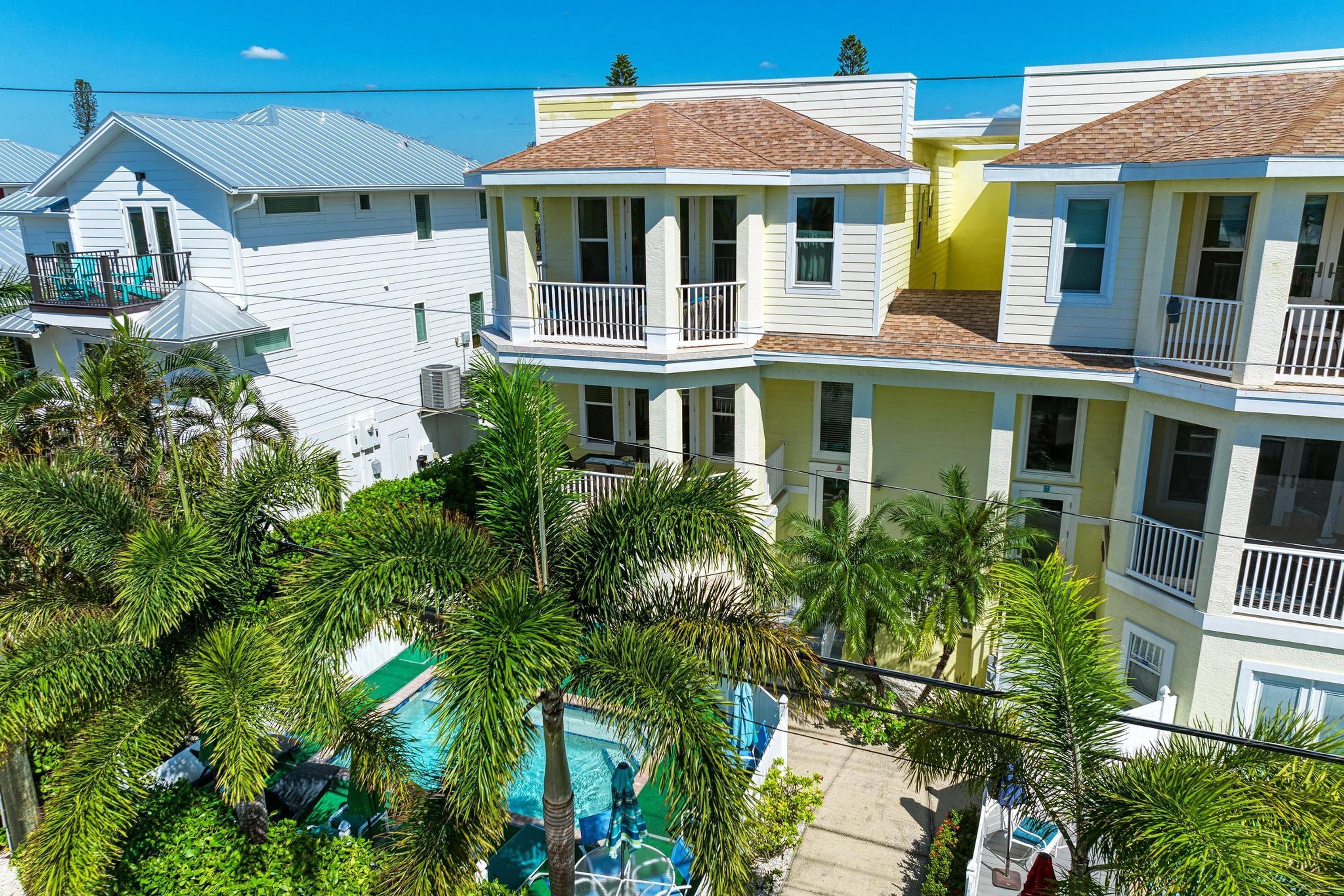 Un edificio residencial de varios pisos con balcones, piscina y abundante vegetación.