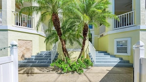 Ein Gebäude mit gelber Fassade, weißen Geländern und einer Treppe, die zu einer oberen Ebene führt.
