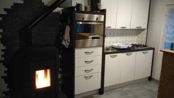 Une cuisine équipée d’une cuisinière intégrée, de meubles blancs et d’un escalier en bois.