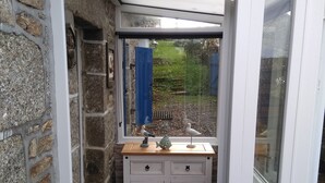 Une pièce étroite aux murs de pierre, avec un banc en bois et une armoire blanche dotée de tiroirs.