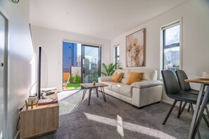 Un soggiorno moderno con divano, tavolino e poltrone, un balcone con vista e un quadro appeso al muro.