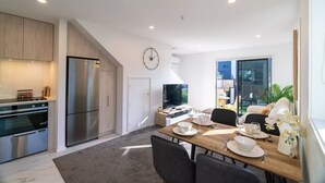 Una cucina moderna con elettrodomestici in acciaio inossidabile, una zona pranzo con tavolo e sedie in legno, e un'ampia finestra con vista sull'esterno.