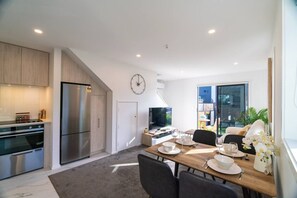 Una cucina moderna con elettrodomestici in acciaio inossidabile, una zona pranzo con tavolo e sedie in legno, e un'ampia finestra con vista sull'esterno.