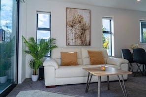 A modern living room with a white sofa, a coffee table, and a large window.