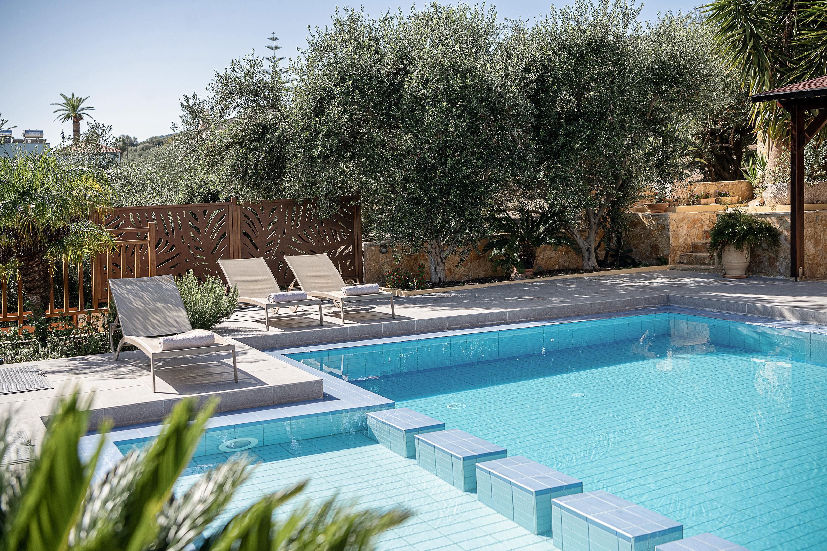 A swimming pool with lounge chairs and a decorative fence.