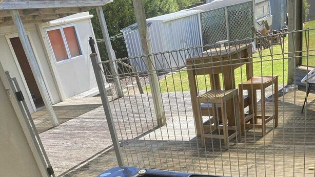 Un bain à remous sur une terrasse en bois, avec vue sur une cour arrière clôturée.
