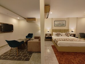 A hotel room with a bed, a desk, a chair, a television, and a wall-mounted air conditioner.