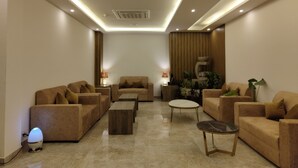 A modern living room with sofas, a coffee table, and a lamp. - Regenta Inn Greater Noida (Greater Noida)