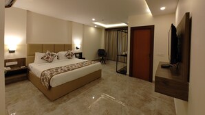 A modern hotel room with a large bed, a flat-screen TV, a desk, and a chair. - Regenta Inn Greater Noida (Greater Noida)