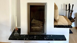 Uma sala de estar moderna com lareira, uma rosa decorativa e um candelabro.