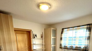 Quarto com cama, guarda-roupa, estante e janela com cortinas.