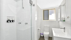 Un baño moderno con cabina de ducha de vidrio, inodoro y lavabo.