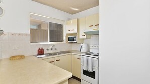 Cocina con pileta, estufa, microondas y ventana.