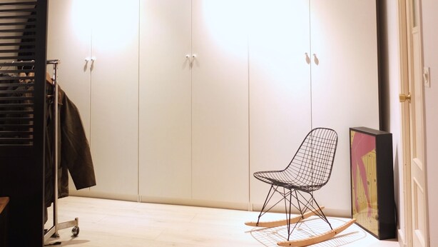 Ein Zimmer mit Kleiderschrank, Stuhl und Kleiderhaken.